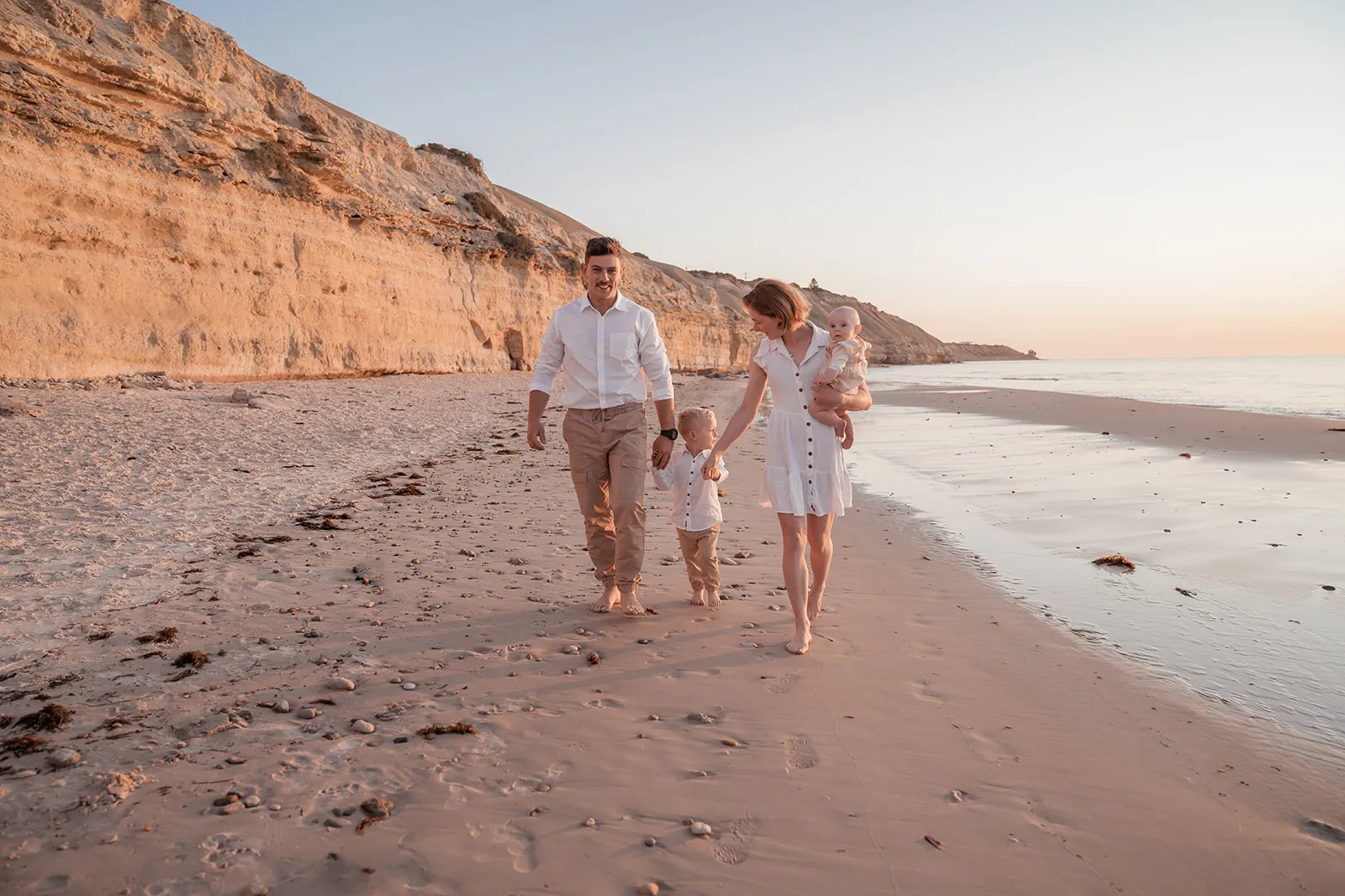 A family walking together across a wide beach landscape on the Fleurieu Peninsula