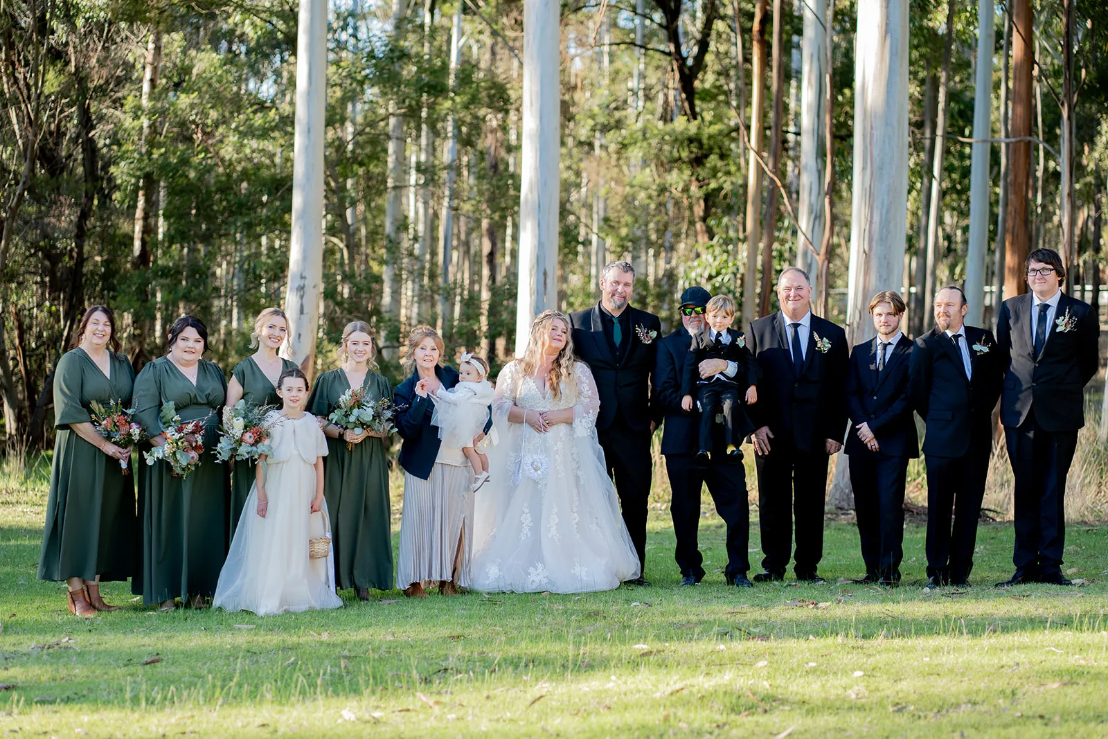 The full wedding party gathered in a woodland setting