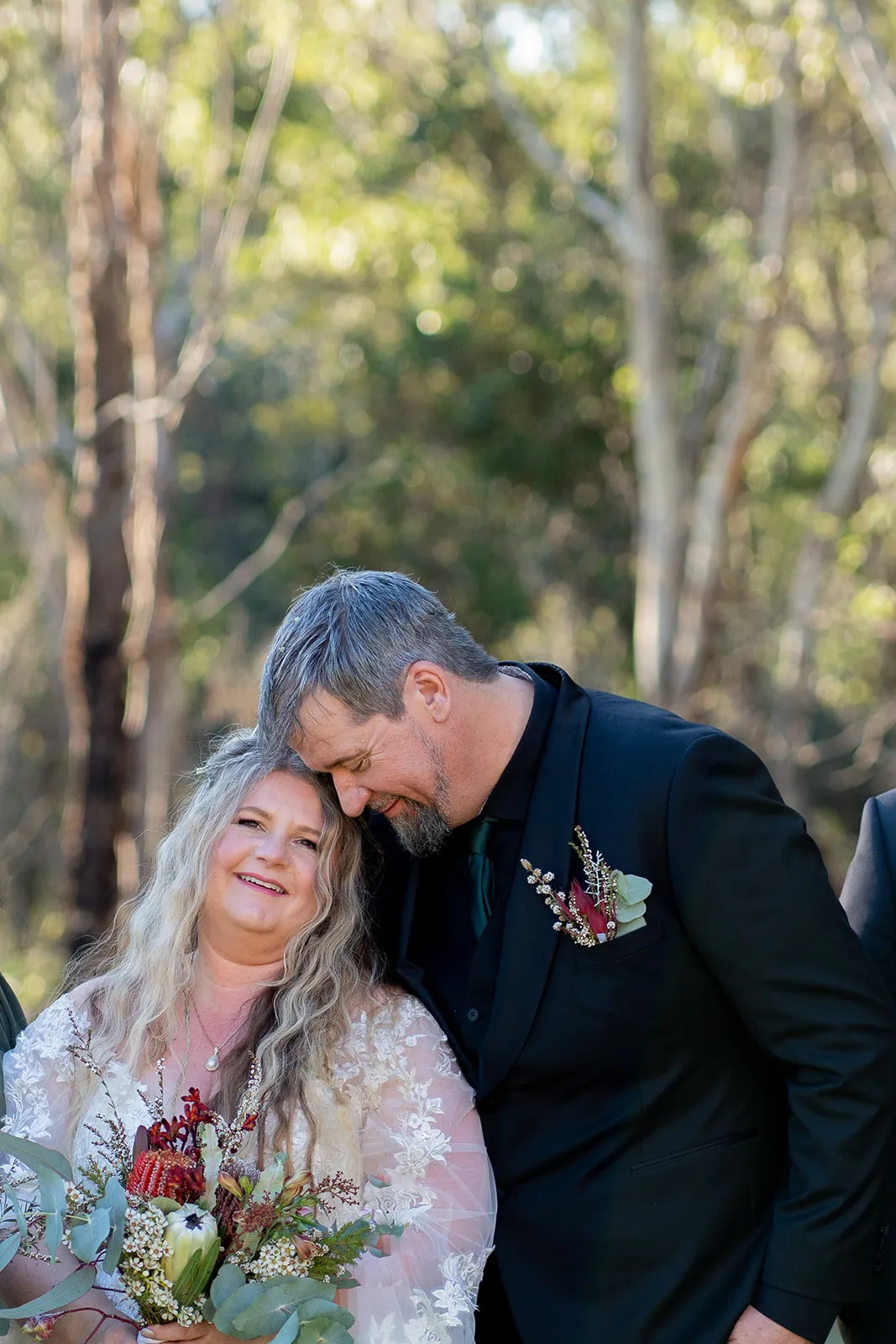 Newlyweds in a relaxed close embrace among the trees