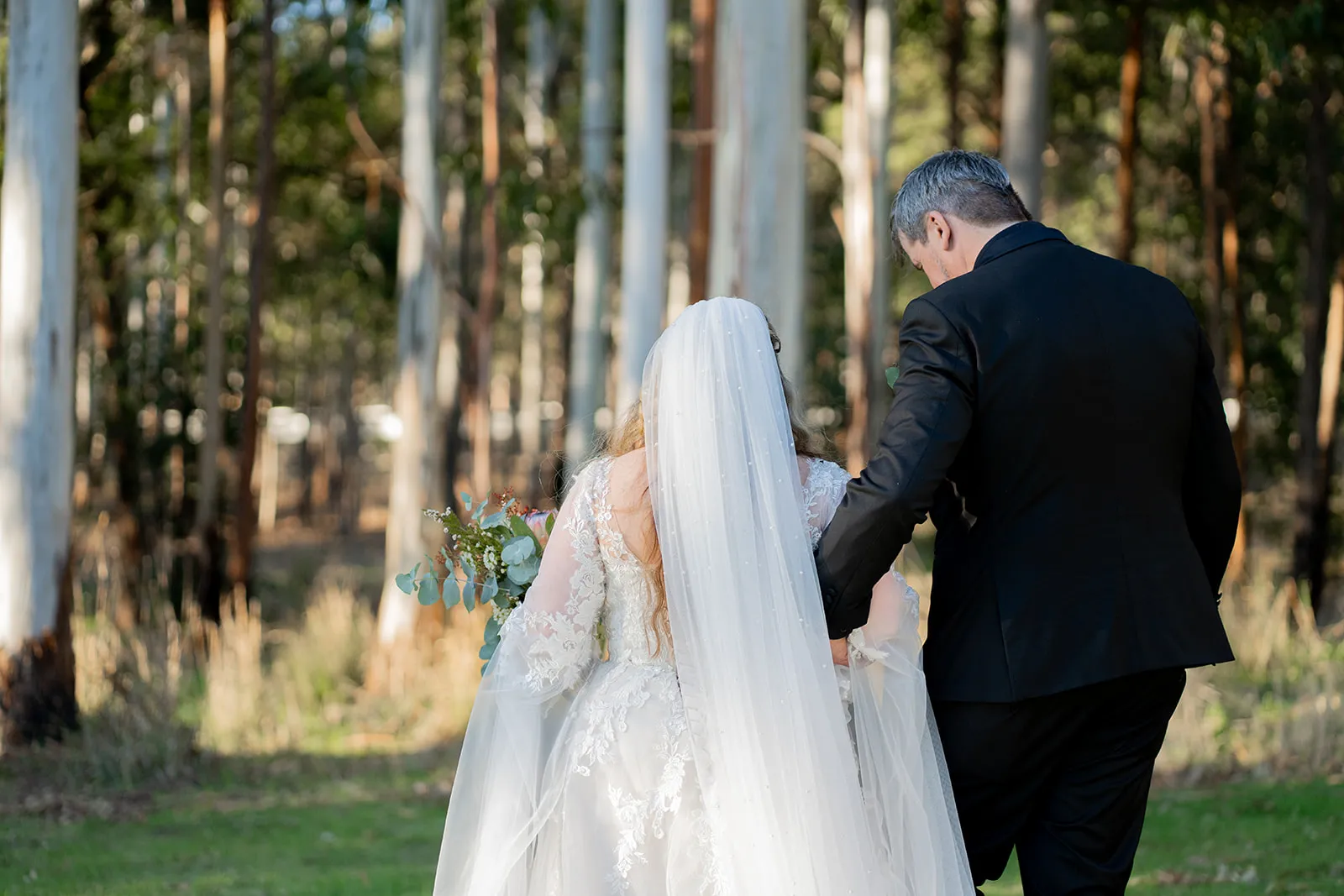Newlyweds walking hand in hand into the trees